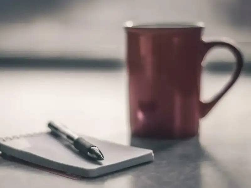 Notepad with pen and cup