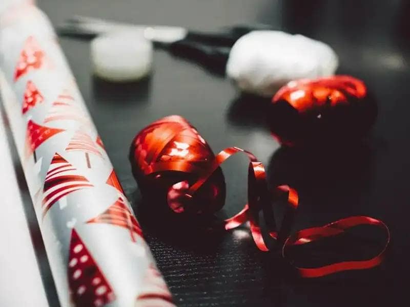 Red and white wrapping paper, ribbon and black scissors on a table